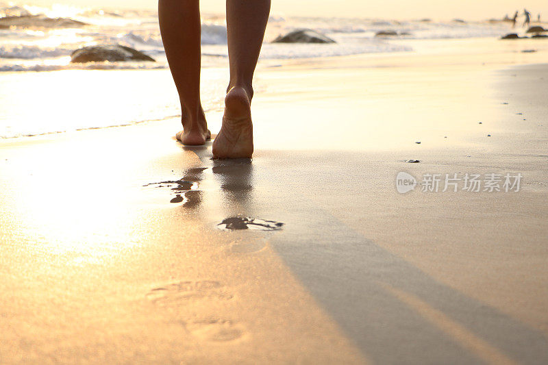 女孩走在潮湿的沙滩上，留下脚印