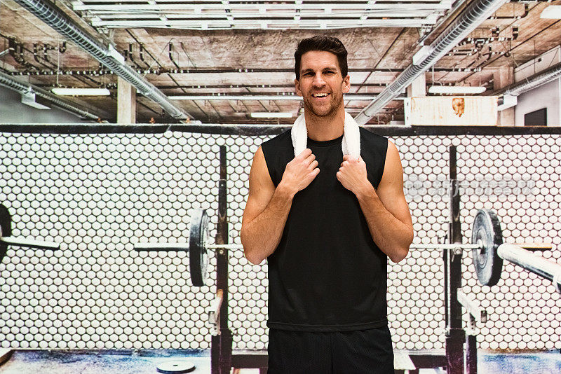 微笑的肌肉男站在健身房