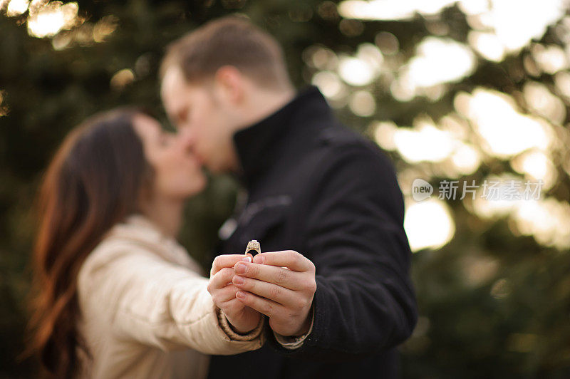年轻的情侣拿着结婚戒指接吻