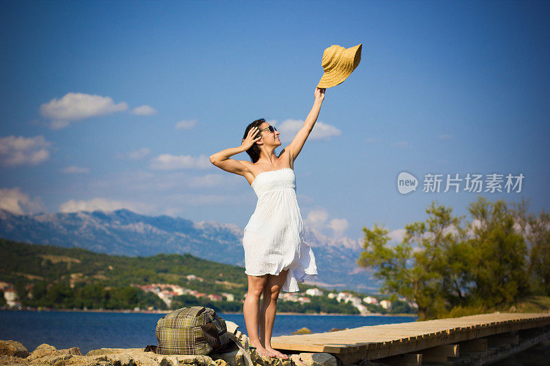 漂亮的女孩在海滩上挥舞着帽子