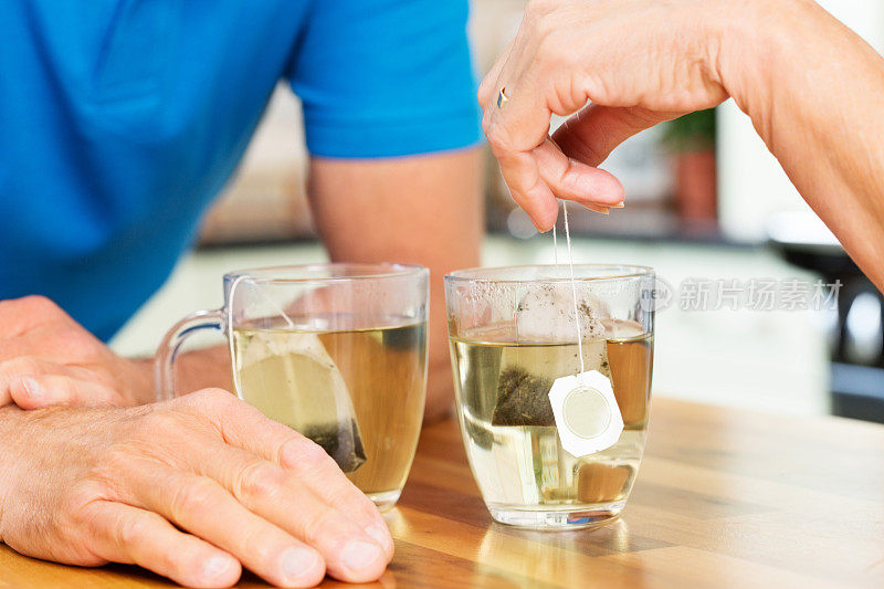 老年夫妇在餐桌上喝茶。