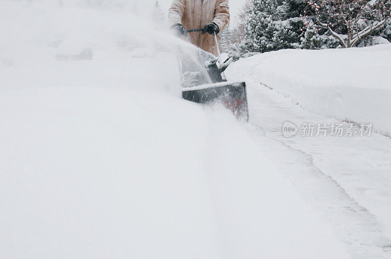 暴风雨中推着吹雪机的人