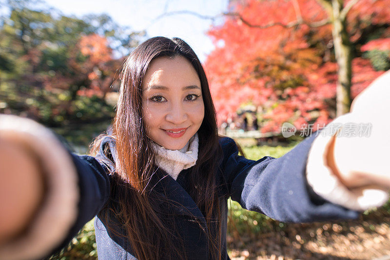 一个女人在秋天的公园里自拍