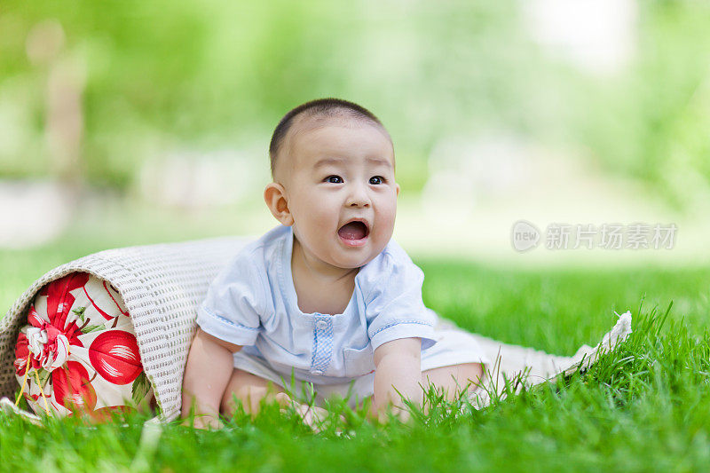 可爱的亚洲小男孩坐在草坪上