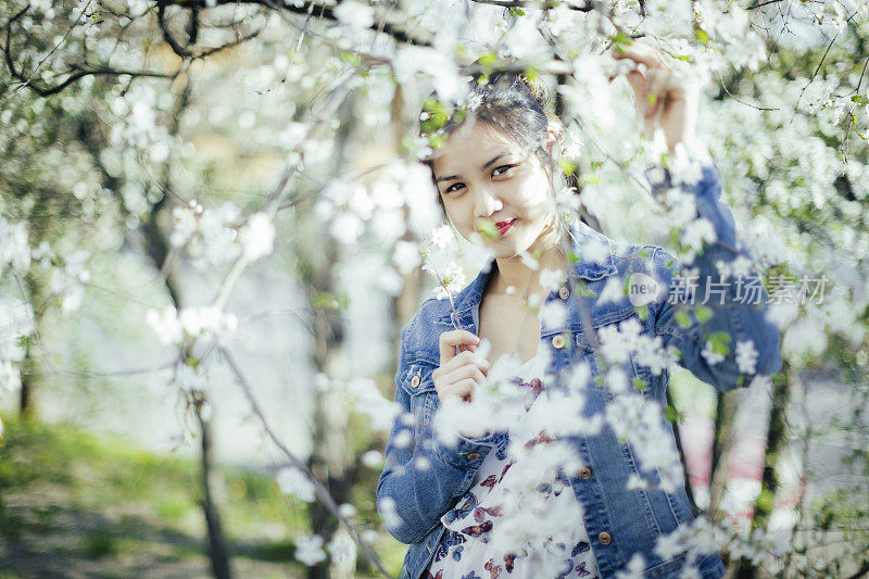 春天的肖像，一个神秘的亚洲女孩在盛开的树木