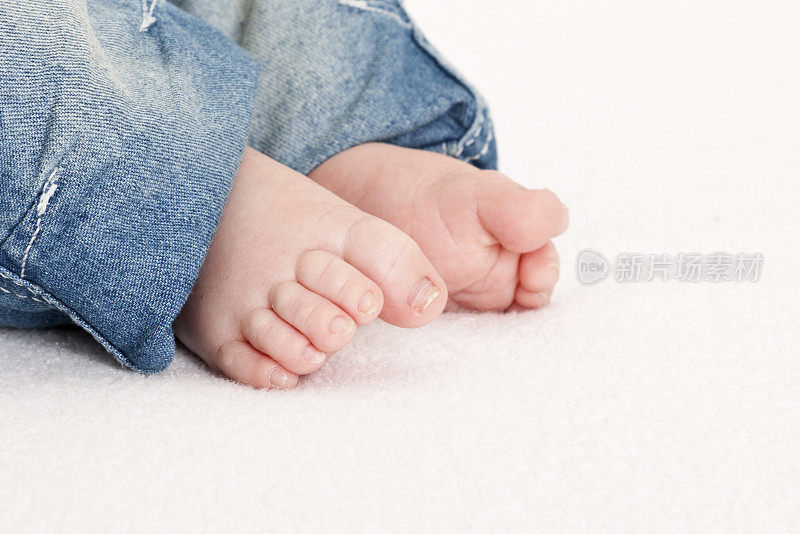新出生的婴儿的脚露出蓝色的牛仔裤