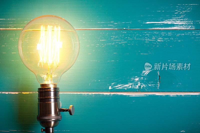 古董白炽灯爱迪生型灯泡在绿松石木桌