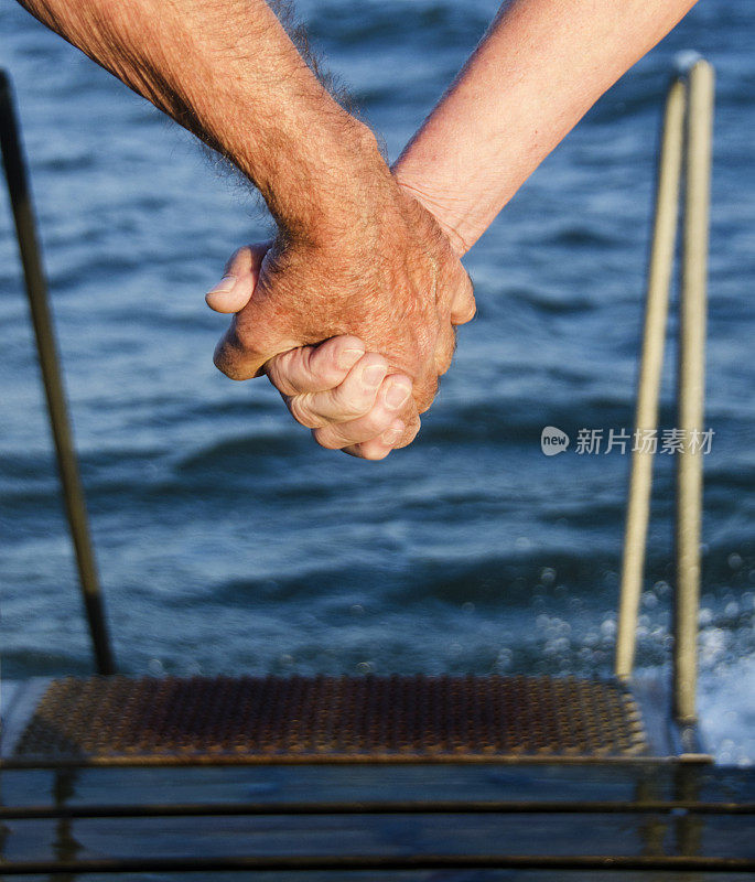 老夫妇洗完海水浴后在码头上手拉手