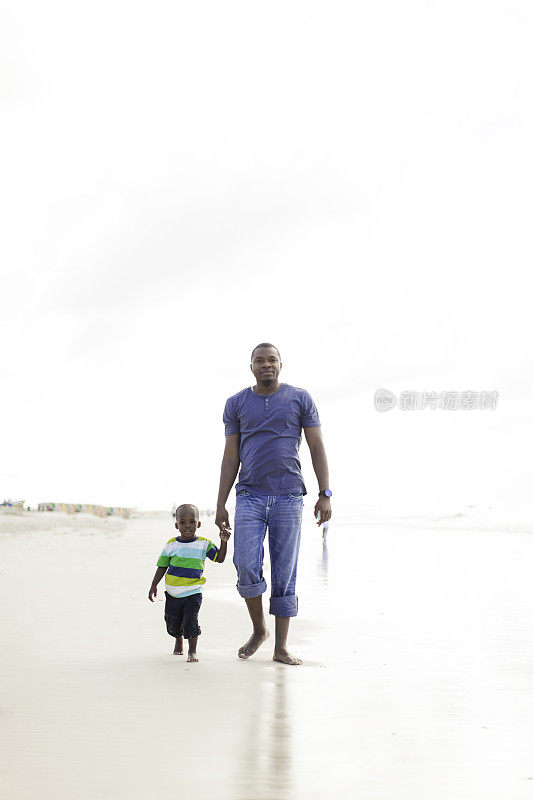 非洲父亲和儿子在海滩上散步