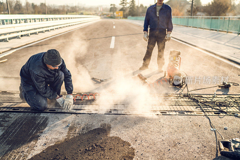 在桥上进行道路维修的体力工人。