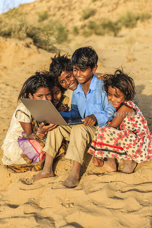 一群快乐的吉普赛印度儿童使用笔记本电脑，印度