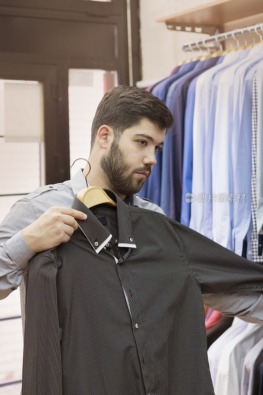 一个年轻人在一家服装店挑选衬衫