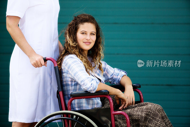 护士用轮椅推着一个美丽微笑的年轻女子