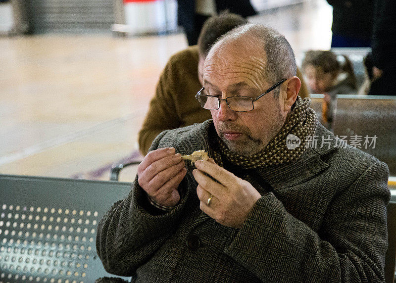 一个成年人在帕丁顿车站吃鸡腿