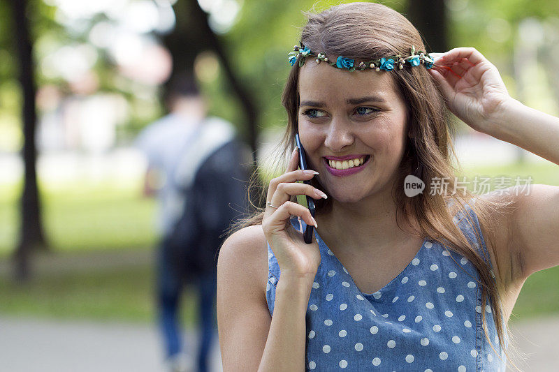 一个迷人的年轻女子正在公园里和手机聊天