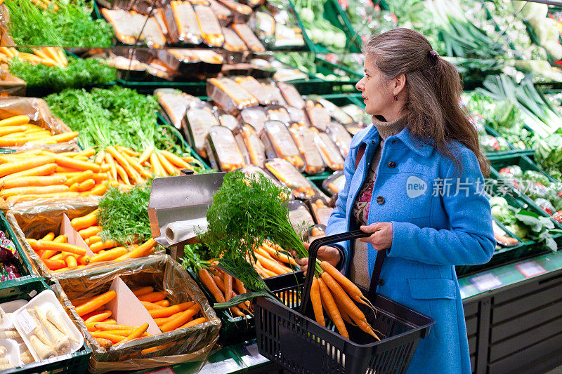 购物:成熟的女人选择新鲜的蔬菜