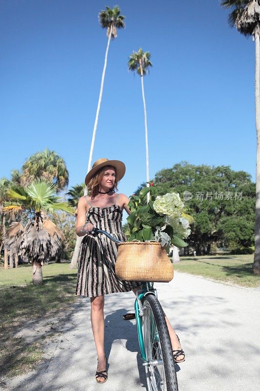 在热带公园里骑自行车的女人。