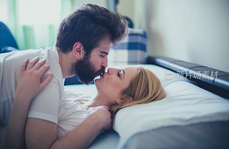 清晨，一对年轻的情侣在床上接吻