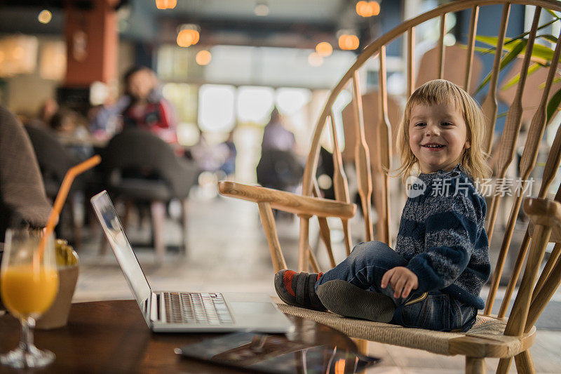 快乐的小男孩坐在咖啡馆的椅子上享受。