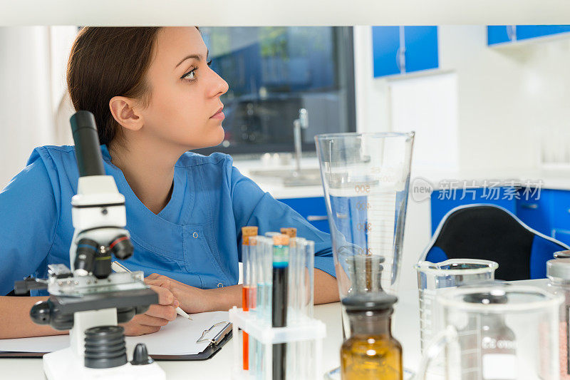 年轻的女科学家穿着制服在实验室做一些研究的肖像