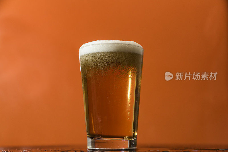 比尔森啤酒杯在橙色的背景