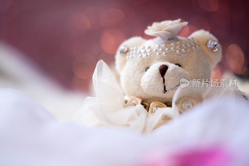 特写图像的小泰迪熊娃娃坐在白色地毯上模糊的粉红色散焦背景