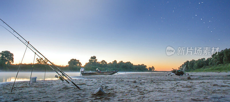 渔船和摩托艇在河上的夕阳下