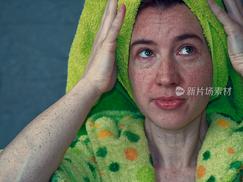 一个女人正在用绿色的毛巾擦头发