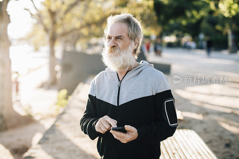 资深男性跑步者正在浏览智能手机