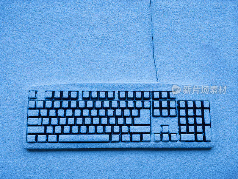 电脑键盘上覆盖着雪，并被蓝色的霓虹灯照亮