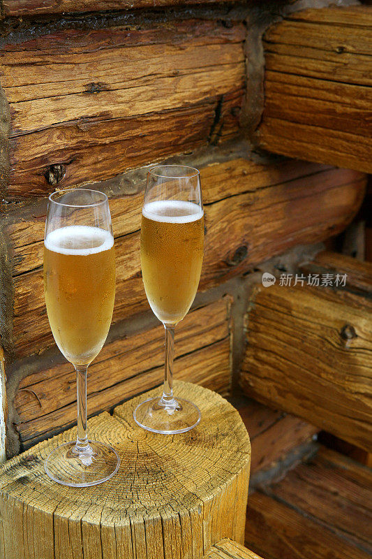 两杯满的香槟放在木屋墙前