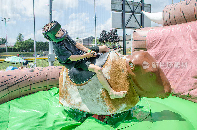 在家庭节日期间，戴着保护头盔的小男孩骑着机械公牛