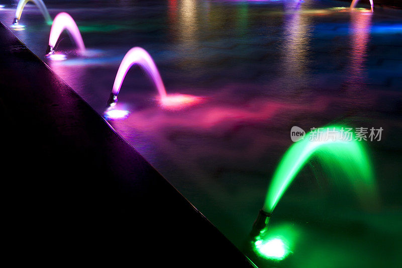 在黑暗的夜晚跳舞的彩色喷泉