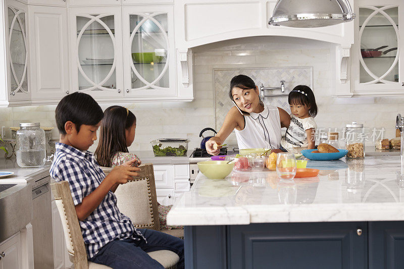 忙碌的母亲在厨房里安排孩子们吃早餐