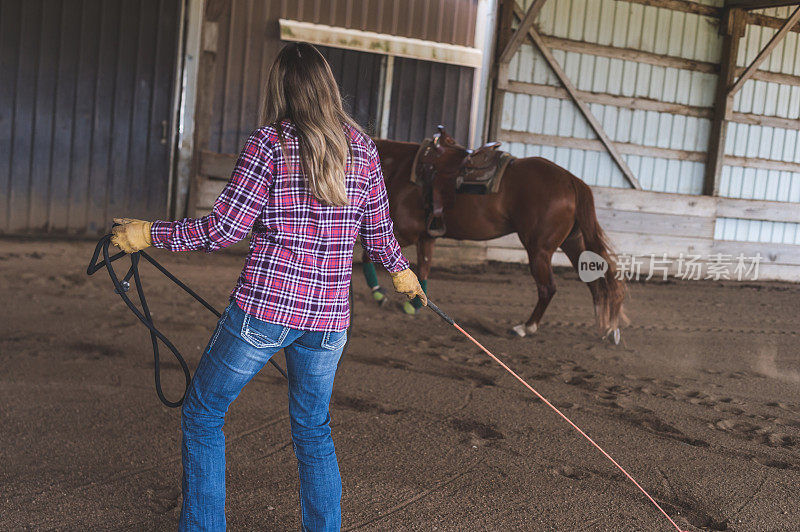 在马厩里训练她的马的女人