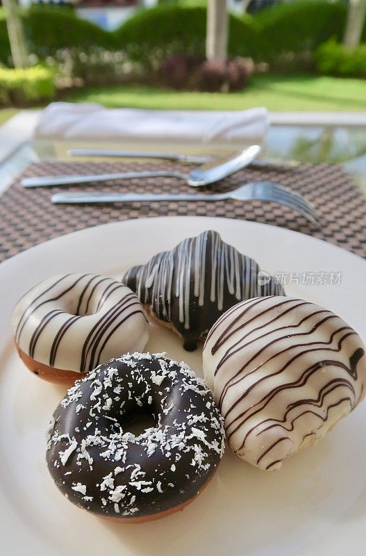 黑色和白色的甜甜圈和糕点冰早餐牛角面包在盘子，甜甜甜圈与巧克力糖衣照片
