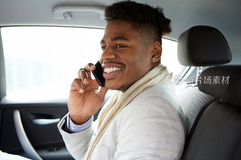 迷人的年轻非洲裔美国人坐在汽车后座上和手机聊天