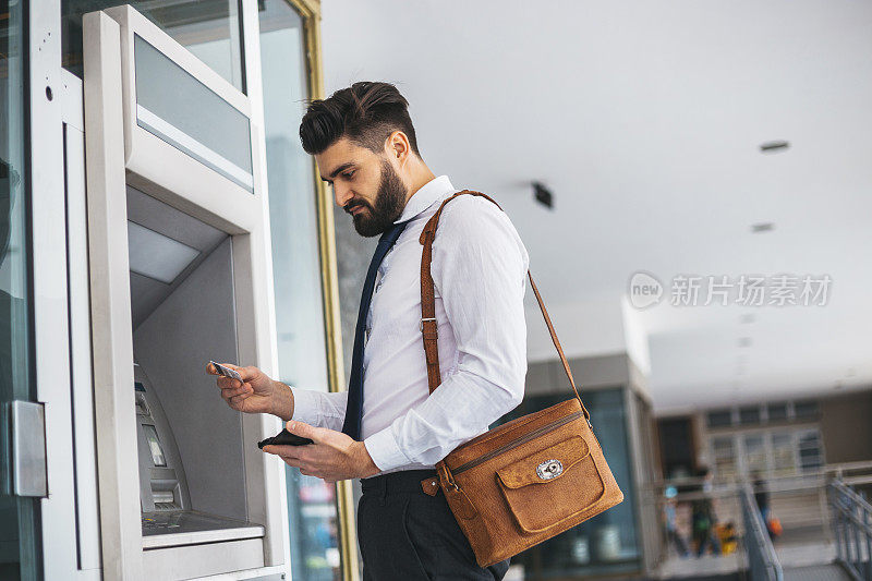 在ATM机上刷卡的商人