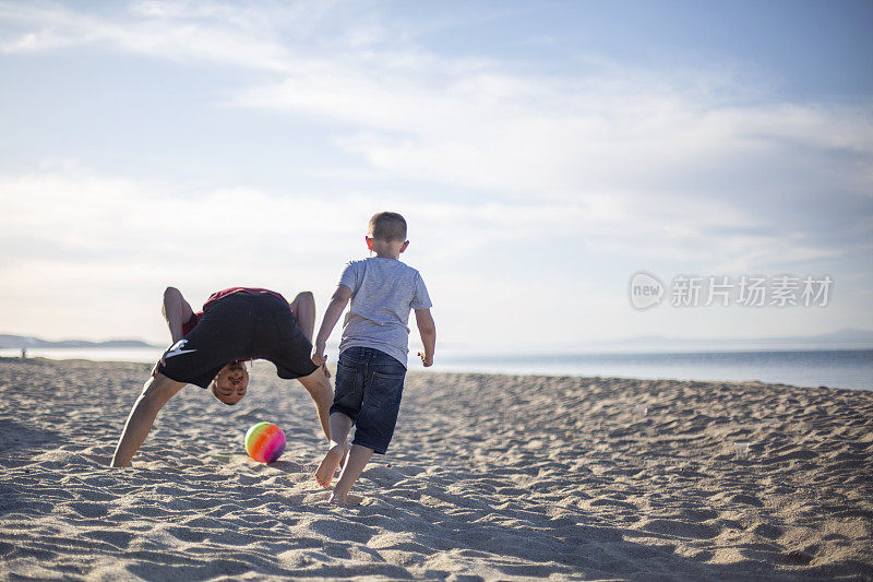 父亲和儿子们在海滩上踢足球