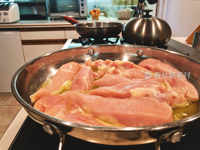 烹饪生柠檬鸡类食物，在煤气炉上用不锈钢平底锅烹饪