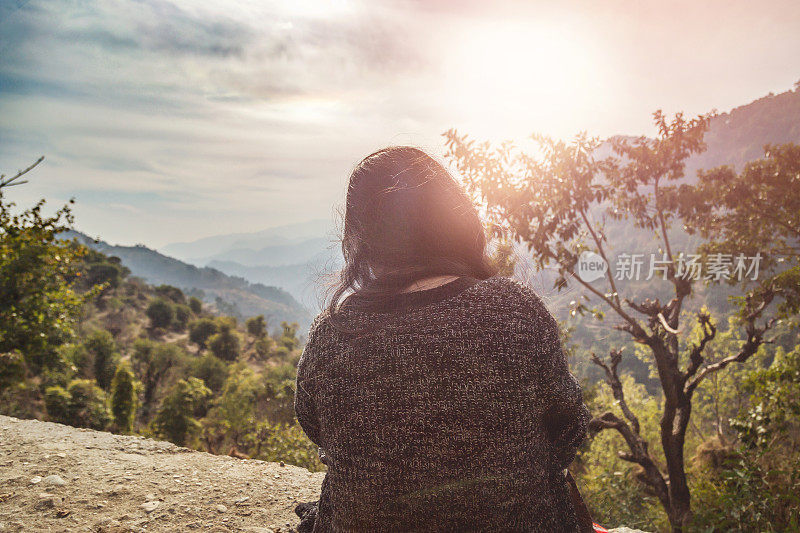 《背谷背山坐在悬崖上的女人，日出》的后视图