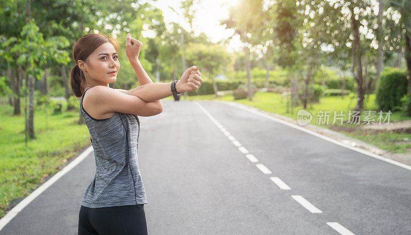 健身女性戴着智能手表做伸展运动，伸展她的手臂、三头肌和肩膀。女人在跑步或锻炼前做伸展运动。