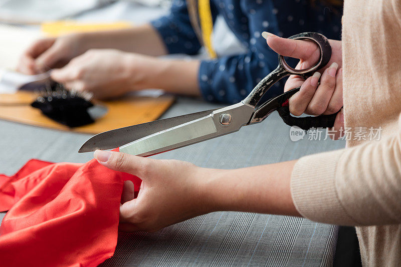 女性的手在裁缝工作场所裁剪衣服
