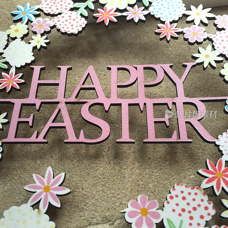 复活节节日装饰标志的形象，木制雕刻的字母说复活节快乐围绕着一圈春天的鲜花