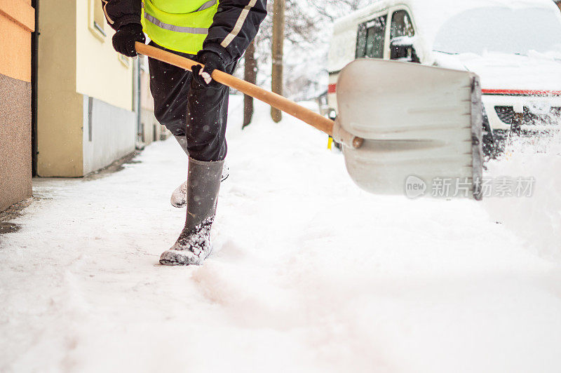 有人用雪铲清扫人行道