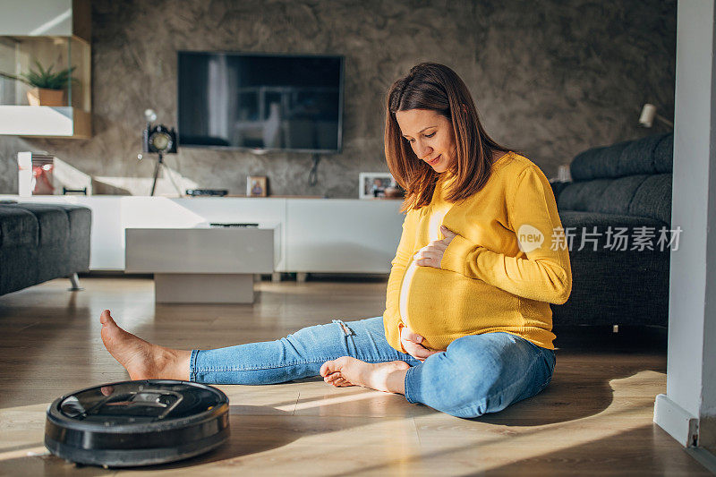 孕妇休息时，机器人真空吸尘器打扫地板