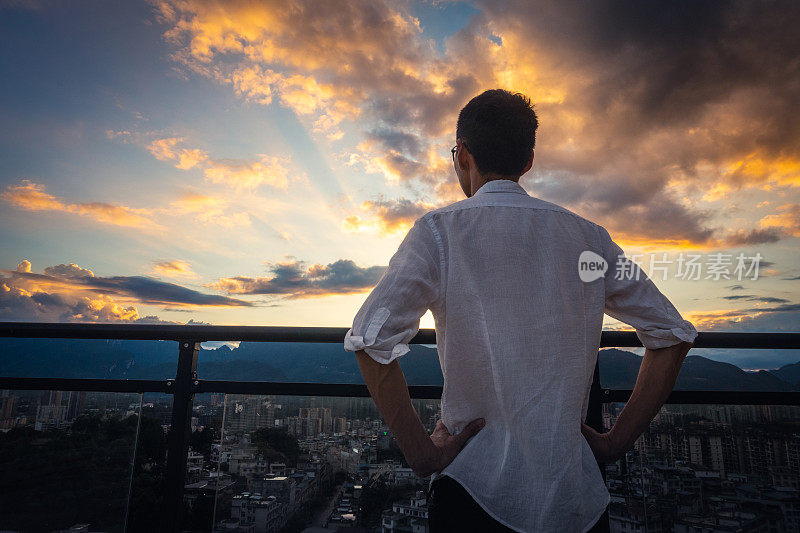 一个年轻人在屋顶上看城市日落
