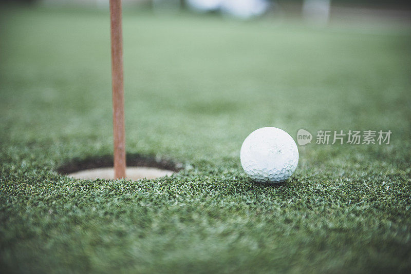 近距离拍摄的高尔夫球旁边的洞在一个高尔夫球场