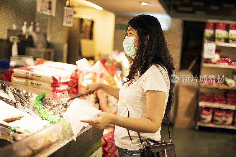 年轻女子在杂货店购物，戴着防护医用口罩