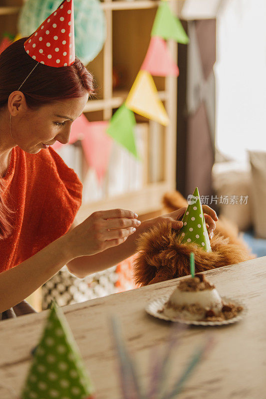 在她的狗一岁生日庆典上，一位女士给它戴上了派对帽